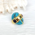 Vista macro di un anello placcato oro con turchese irregolare e pietre preziose incastonate - Anello Turchese Pietre Miste