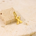 Macro shot of polished gold letter X pendant on a textured minimalist stone surface - Letter-X / Steel