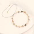 Detail of handmade beaded bracelet with natural stones and adjustable braided cord - Gray