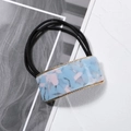 Detail of square marble acetate hair tie with golden serrated metal edge and black band - Blue
