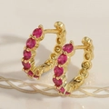 Détail macro de boucles d'oreilles huggie dorées avec zircons rouges ronds - Zircone Rouge Rose
