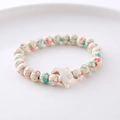 Handmade beaded bracelet with turquoise patterns and white dolphin charm detail - Beige Turquoise Red Spotted White Dolphin