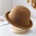 Detail of camel wool felt bucket hat texture with a small side label on a wooden stand - Khaki