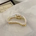 Detail of elegant wavy pearl white claw clip with pale gold metal frame for hair - Mermaid Color