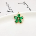 Macro shot of a gold flower pendant with five marquise-cut green zircon petals on ceramic - Green