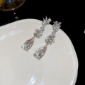 Macro view of crystal drop earrings with leaf motifs on a ceramic tray over black background - Silver (Silver Pin)