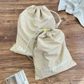Dettaglio di sacchetti beige con coulisse e chiusure a sfera gialle su legno scuro - Piccolo / Marrone