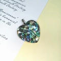 Detailansicht eines herzförmigen Mosaik-Abalone-Muschelanhängers mit silbernem Metallverschluss - Herz