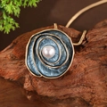 Dettaglio di un ciondolo a rosa dorata con smalto blu e perla su sfondo in legno rustico - Ciondolo Perla Rosa Blu - Oro