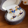 Detail van gouden oorringen met blauwe emaille vlinders en witte parels op fluweel - 13# Zilveren pin - Goud Blauw Vlinder Ring Parel