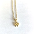 Macro shot of minimalist gold necklace featuring a letter W pendant on white texture - Letter W