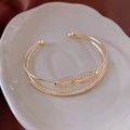 Vue détaillée du bracelet jonc ouvert doré à double couche orné de cristaux étincelants - Jonc Entrelacé Double Couche Or