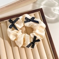 Beige satin scrunchie with delicate black bows on a velvet jewelry tray - White Band Black Bow