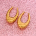 Detalle macro de pendientes en forma de U dorados con rayas verticales sobre purpurina rosa - Estilo de Rayas con Nervaduras / Dorado