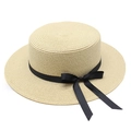 Détail du chapeau de paille tissé avec un nœud en ruban de grain noir sur fond blanc - Beige