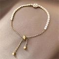 Close-up of golden adjustable tennis bracelet with sparkling zircon halo centerpiece - Gold