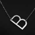 Minimalist silver chain necklace with a capital letter B pendant on a black background - White Letter B