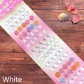 Macro shot of assorted crystal gemstone stickers in star and heart shapes on wood - Shell Series White