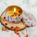 Candela profumata in latta rosa con fiori secchi su un sottobicchiere di legno - Gelsomino