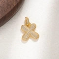 Macro shot of gold cross pendant with micro-pave cubic zirconia on a textured surface - Letter X