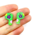 Hand holding green acrylic P-shaped letter pendant with purple flower for DIY crafts - Letter P