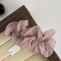 Dettaglio macro di un elastico per capelli in rete rosa plissettata su vassoio di legno - Rosa