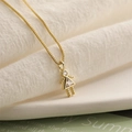 Vue détaillée du collier pendentif fille doré avec une pierre triangulaire brillante - Avril Blanc