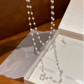 Detail of double-layer faux pearl necklace draped over a white jewelry box - Gold White