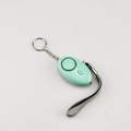 Detail view of a light green personal safety alarm with keychain and grey wrist strap - Emerald Green
