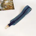 Detail of blue geometric woven wide shoulder strap with leather ends and gold hooks - Blue with Blue Trim