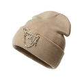 Detail of beige knit beanie featuring metal safety pin, chain, cross, and butterfly charms - One Size / Khaki