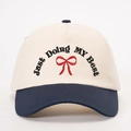 Cream and navy baseball cap with red bow embroidery and JUST DOING MY BEST slogan - Cream/Navy Blue