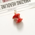 Dettaglio di un ciondolo a mela morsicata in resina rossa con anello dorato per gioielli DIY - Torsolo di mela rossa