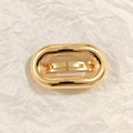 Detailed close-up of a high-polish oval gold metal hair clip on a white textured background - Gold