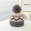 Dettaglio di un cappello invernale in maglia con motivi a cuore e pompon grigio morbido - 2-7 Anni / Grigio