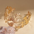 Dettaglio macro del bracciale rigido dorato con intricati motivi di fiori e foglie cavi - Stile Floreale 3D Oro / Oro