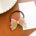Pink and green acetate bow hair tie with pearl accent on brown leather background - Floral Pink Green - Hair Tie
