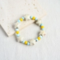 Ceramic star beaded bracelet in beige, light blue, and yellow on a textured stone plate - Starlight (340D)