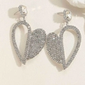 Detailed view of silver heart earrings featuring sparkling rhinestones on beige background - Irregular Heart Style (ES2407-2)