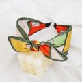 Detail shot of a geometric pattern knot headband on a white decorative stand - Orange Geometric Print Bow Headband