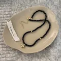 Detailansicht der schwarzen Perlenkette mit goldenem Kreuzanhänger und Verschluss - Schwarz (Kreuz)