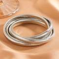 Macro detail of the silver multi-layer snake bone chain bracelet on orange silk - Steel Four-Layer Bangle (R102)