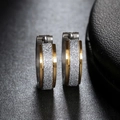 Dettaglio ravvicinato di orecchini a cerchio bicolore in acciaio con trama satinata argento - Oro e Argento
