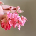 Gros plan de boucles d'oreilles fleurs en mousseline rose avec pompons en perles vertes et métal doré - Style Pampille Bouton de Rose / Rose