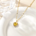 Macro shot of heart-shaped yellow gemstone necklace with pavé zircon trim on white ceramic - May - Golden Yellow