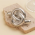 Close-up of a silver twisted knot metal hair ring on a textured stone display - Minimalist Knot Hair Clip / Silver