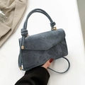 Borsa a tracolla blu denim con manico e dettagli dorati su uno sfondo neutro - Blu