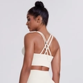 Detail view of crisscross back straps on a cream white sports bra with supportive wide hem - Light Ivory