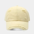 Close-up detail of distressed distressed holes and frayed edges on the cream cotton baseball cap - Light Yellow