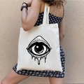 Beige canvas tote bag featuring a black Greek Evil Eye graffiti print shown on shoulder - STD1804-V Black Crying Eye